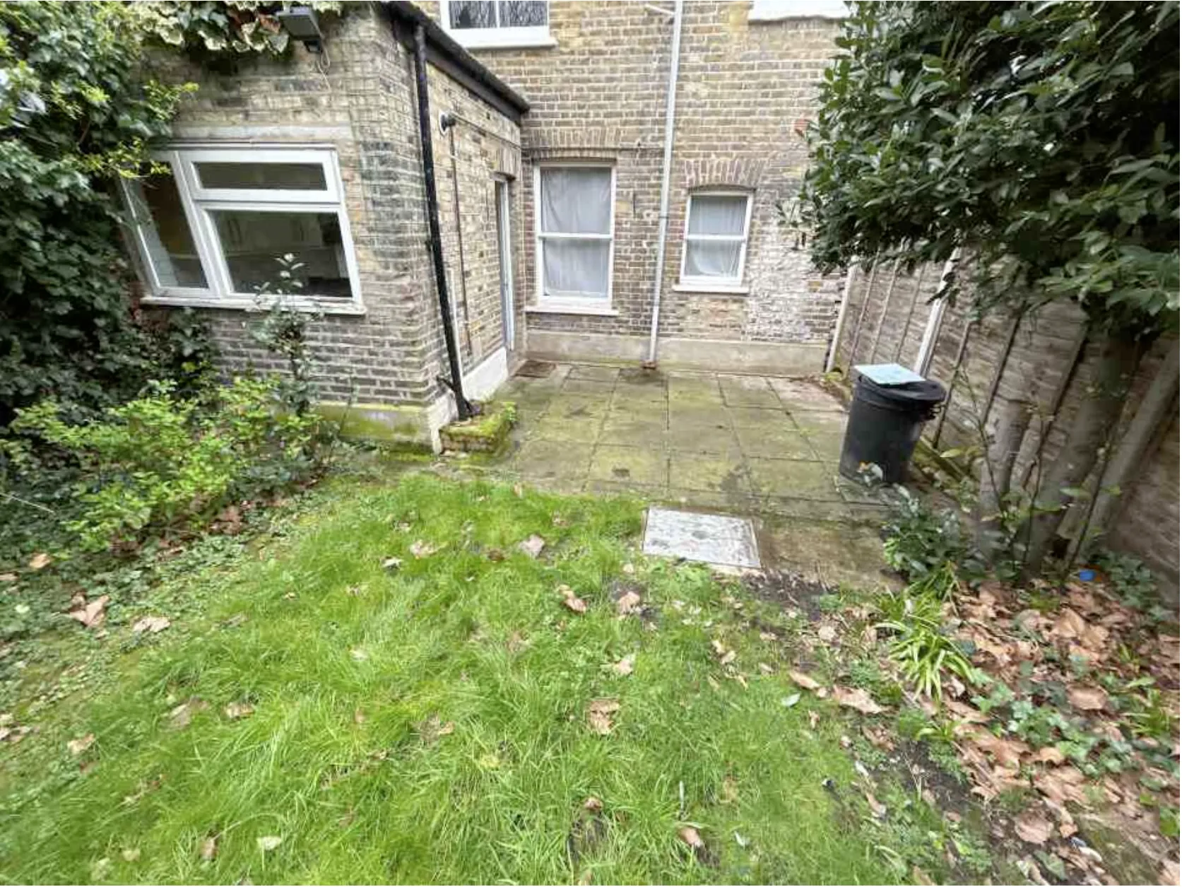 The rear elevation of the property seen from the garden, showing the sash windows and the paved area at the back of the house