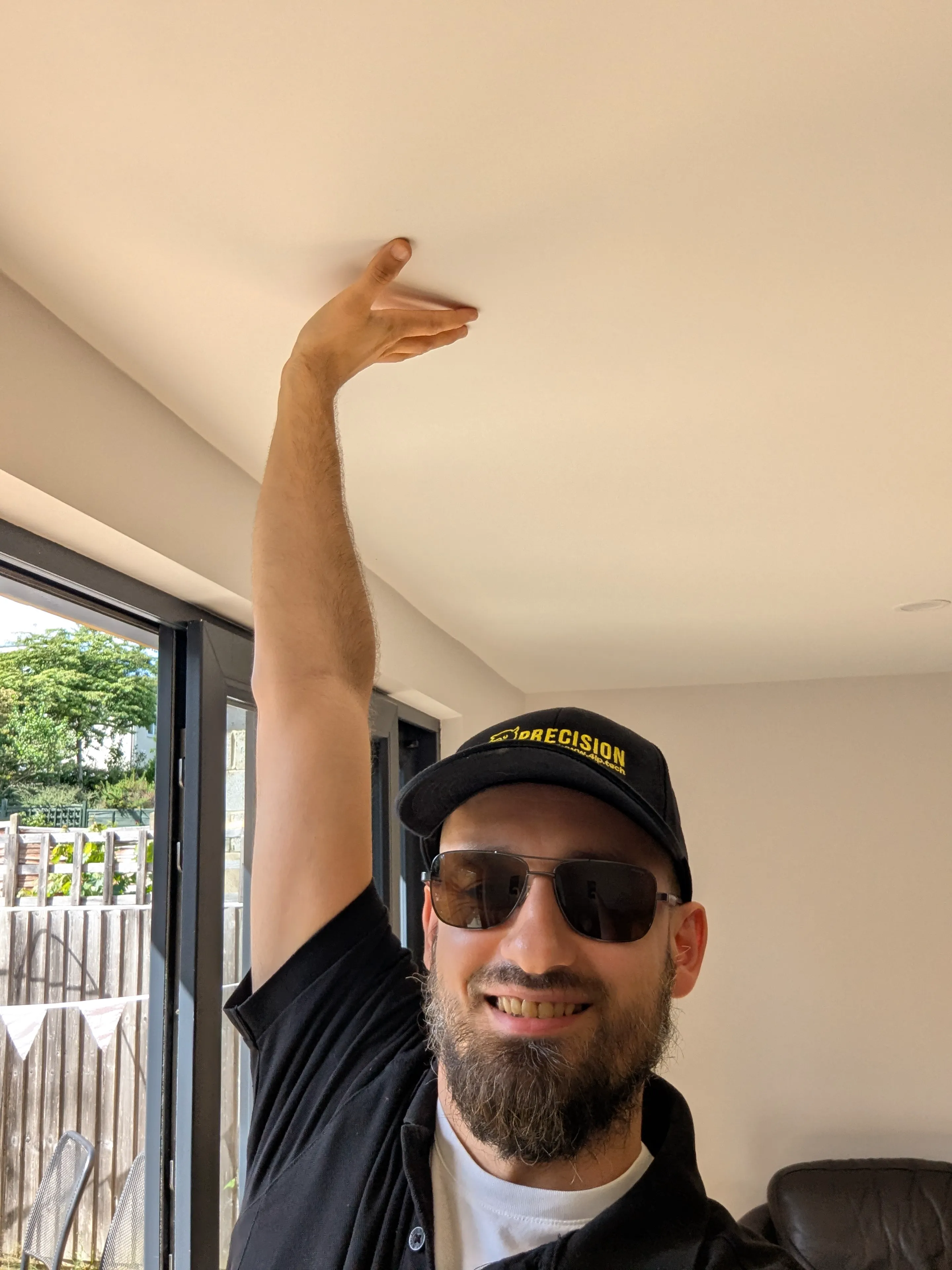 A member of the Precision Rooms team standing inside the finished room reaching up to touch the ceiling