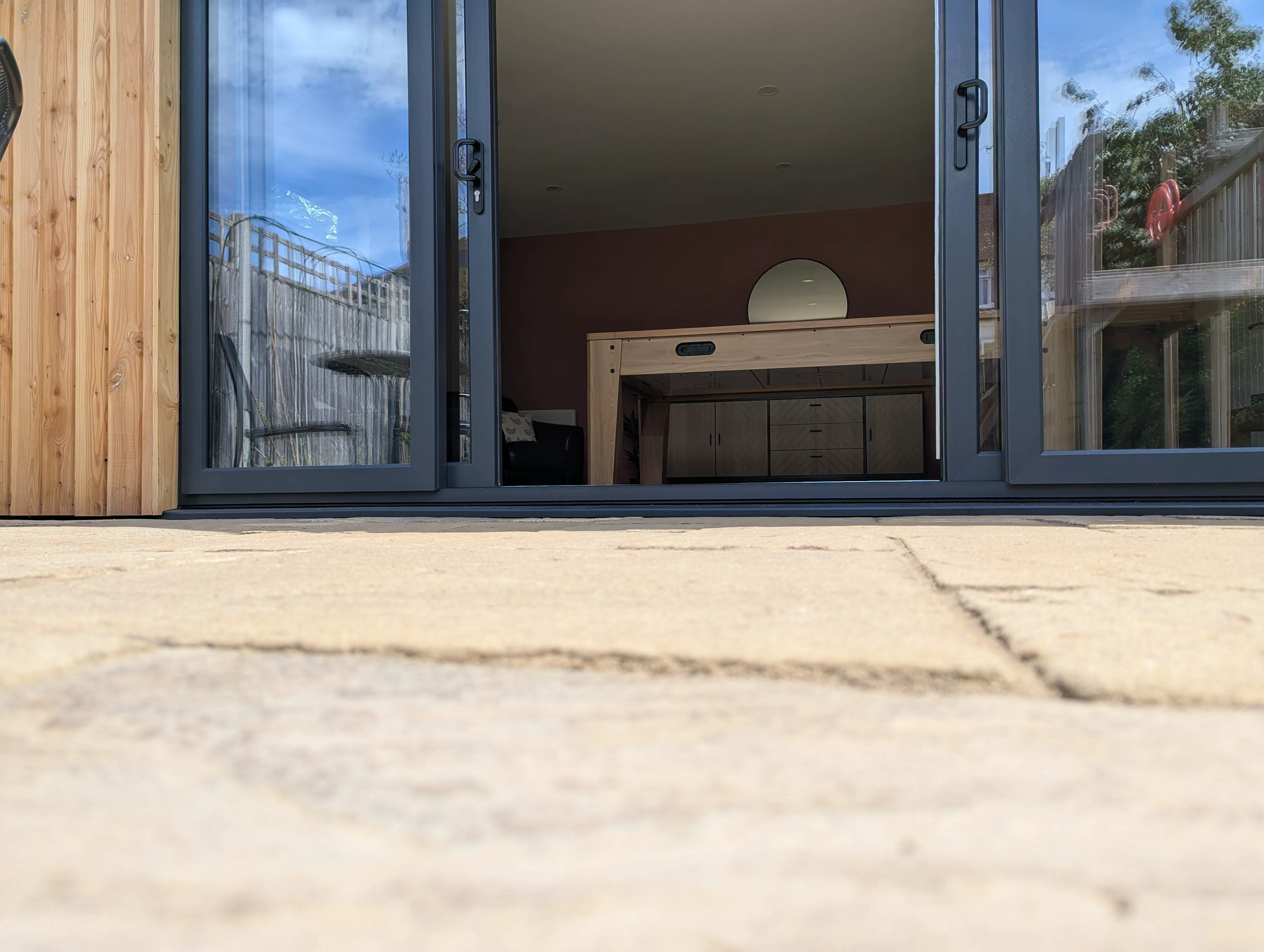 Low angle view along the patio showing the paving running level with the interior floor through the open sliding doors