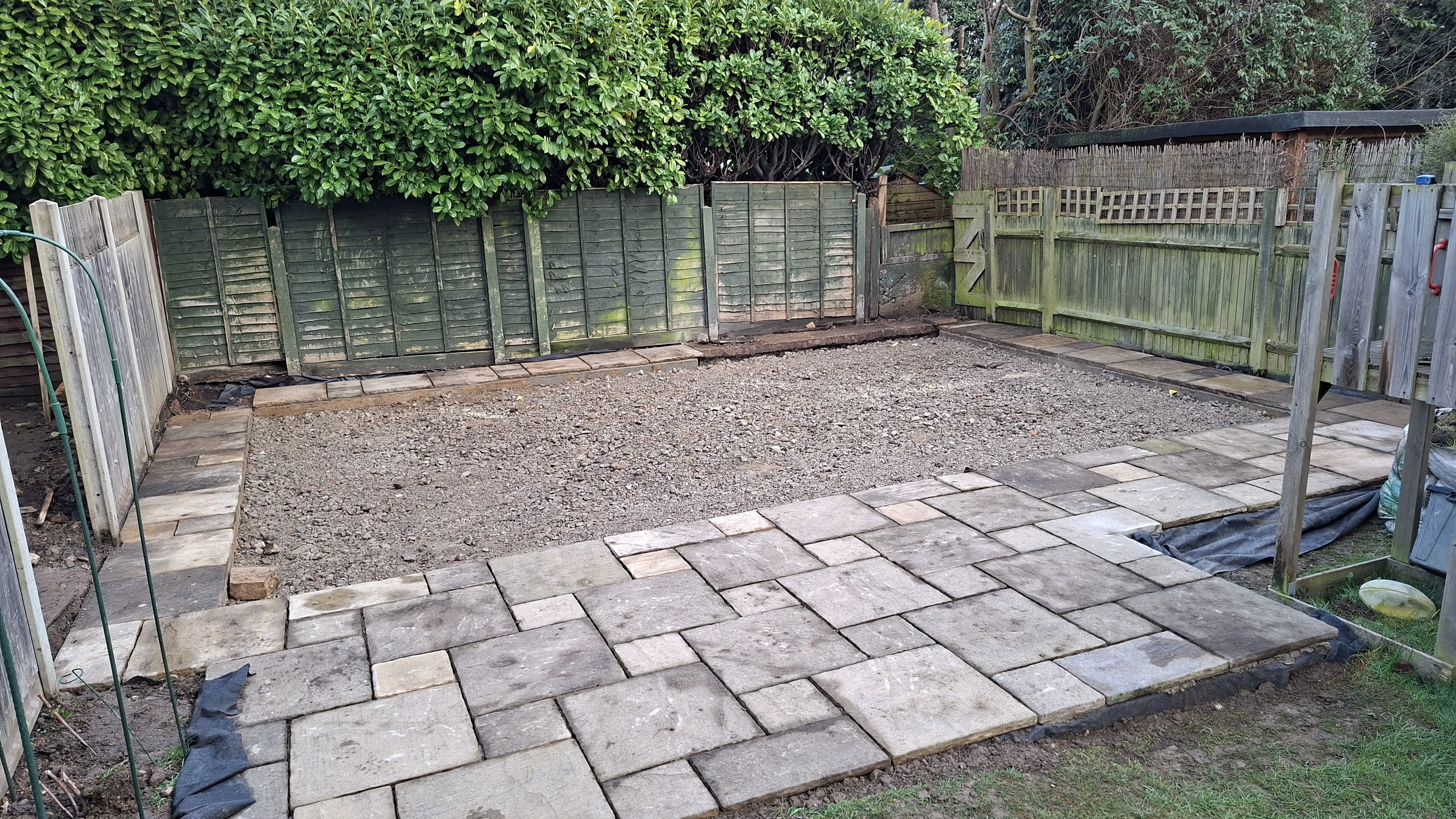 The completed excavation pit filled with MOT Type 3 aggregate, with concrete lintels forming a retaining perimeter and the existing patio in the foreground